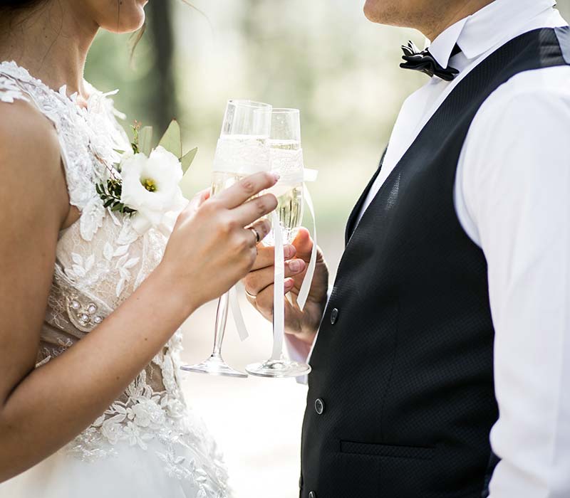 Detalle de dos recién casados brindando con copas de champán.