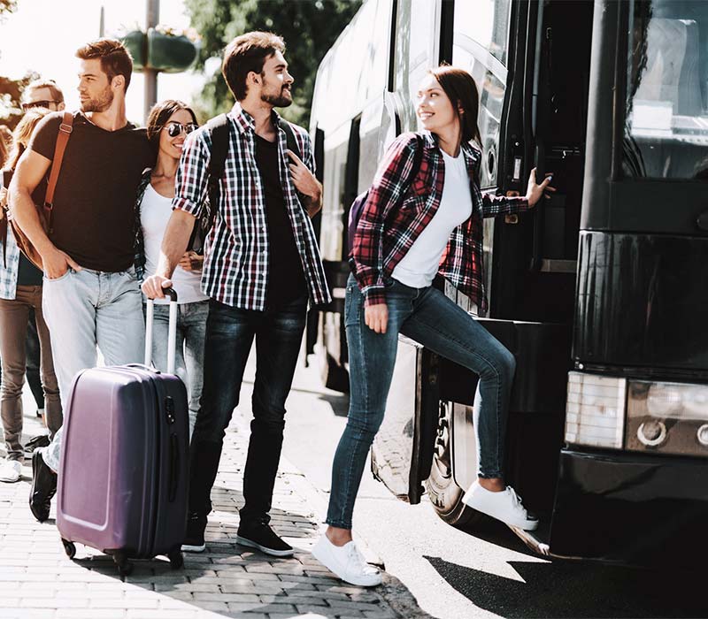 Grupo de jóvenes con maletas subiendo a un autobús.